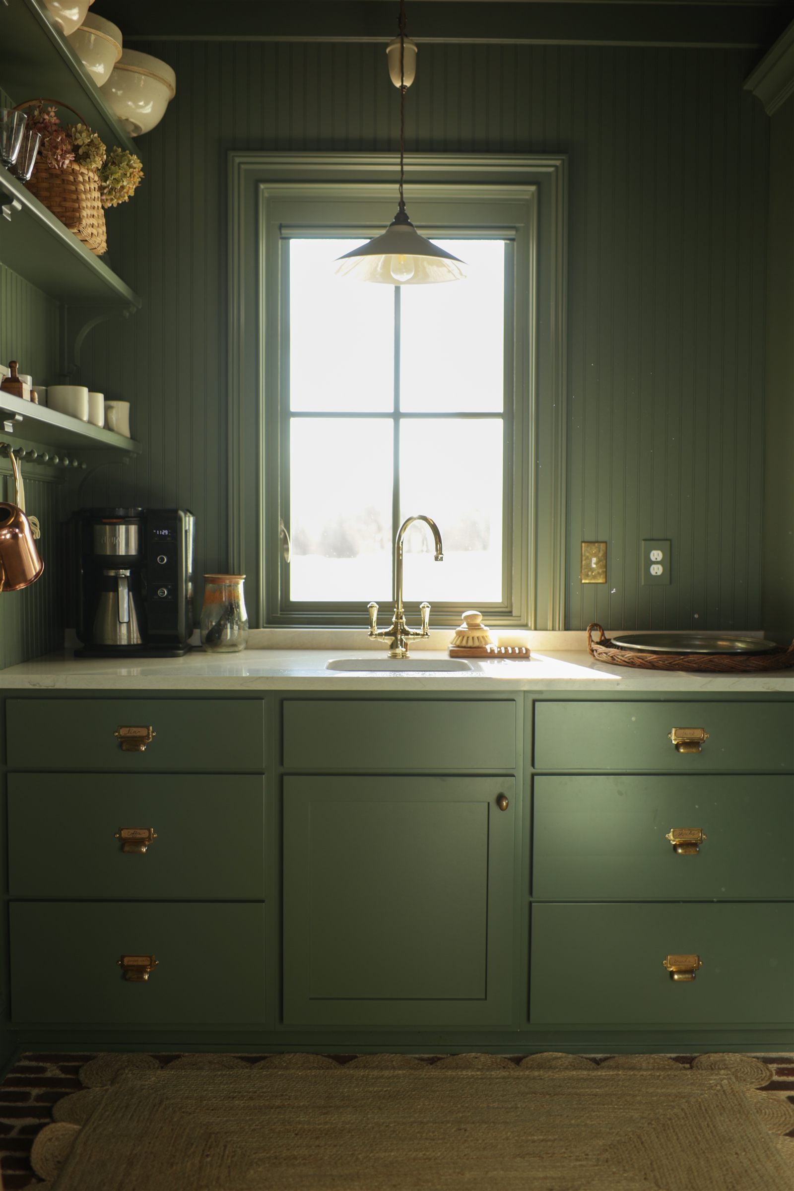 Green mudroom with brass sink and brick floor in a Sage Built home