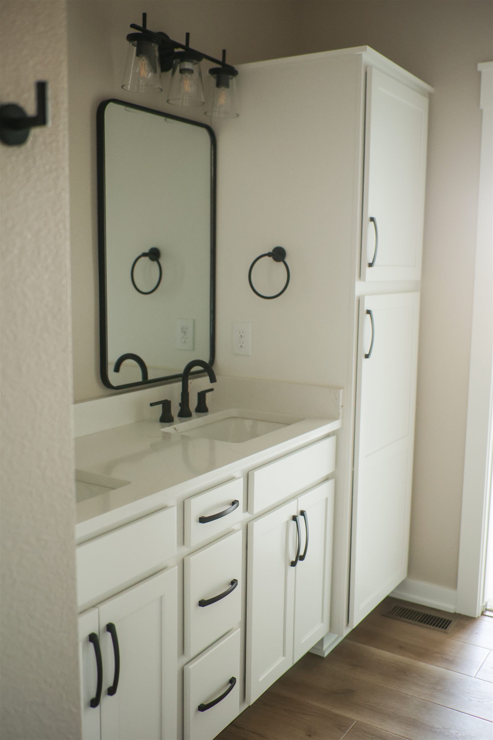 Renovated bathroom with double vanity and linen tower in a Sage Built home